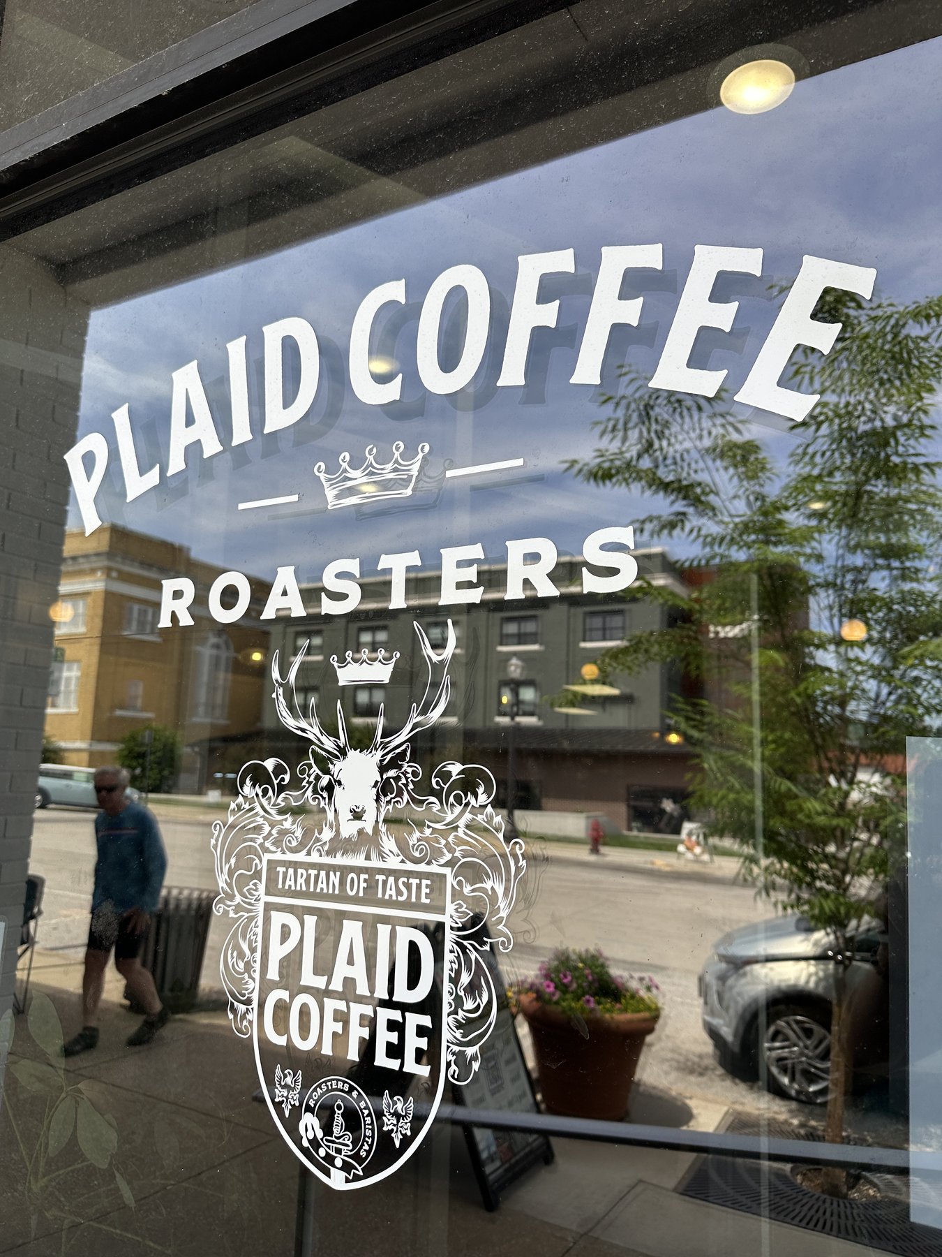 The Plaid Coffee Roasters storefront window with the brand wordmark and tartan-of-taste decal visible through the glass